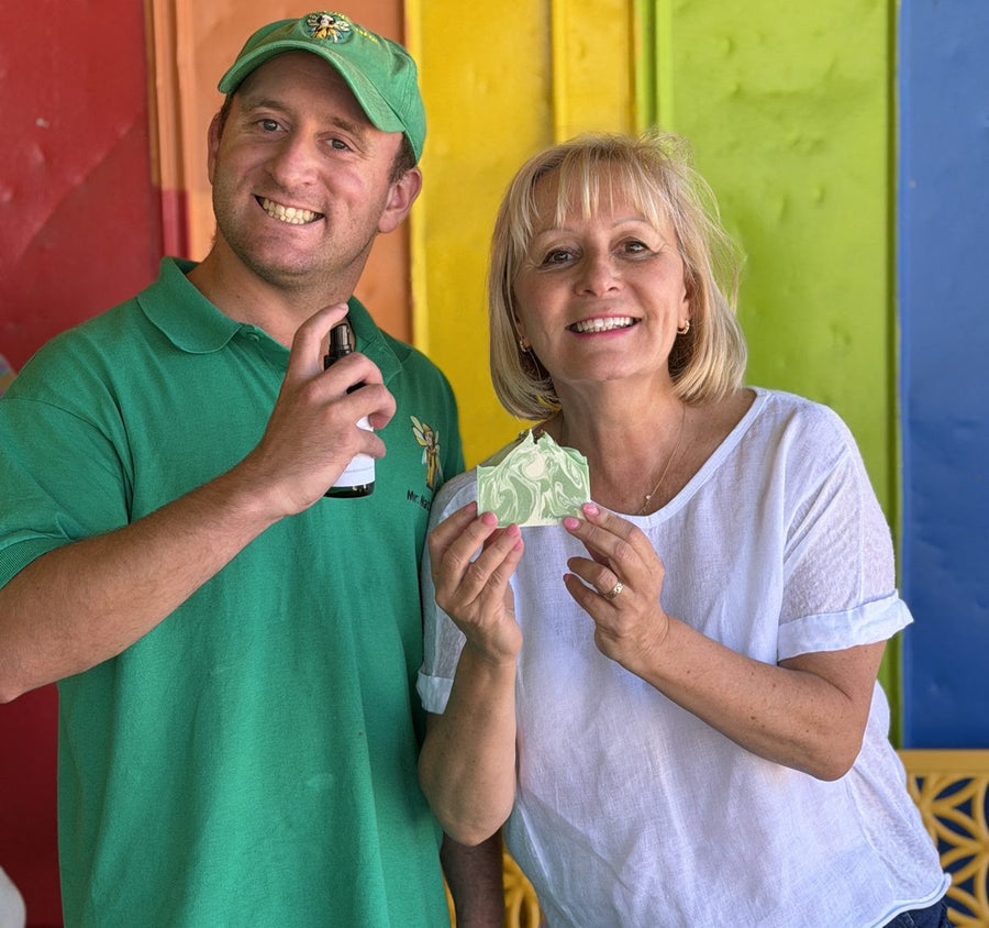 Two Naturalistic Body Care team members holding a spray bottle and patterned soap bar.